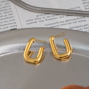 Detailed macro view of 18K gold plated U-shaped stud earrings on a metallic tray