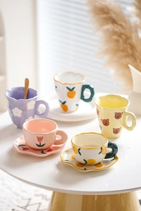 Detailed close-up of cute ceramic coffee cups with hand-painted floral and animal patterns