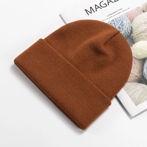 Detailed view of caramel ribbed knit beanie on white background with magazine prop