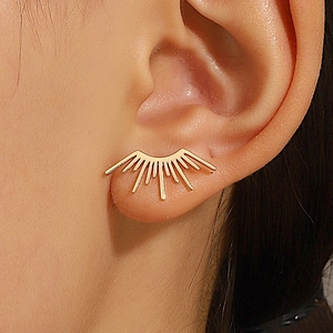 Détail de boucles d'oreilles soleil vintage dorées portées avec un design éclatant métal