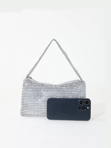 Detailed close-up of sparkling silver rhinestone evening bag next to a smartphone