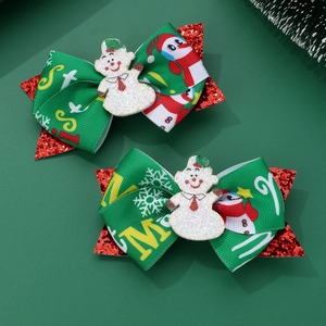 Detail view of green Christmas bow hair clips with snowman resin decor and red glitter