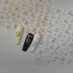 Detailed view of 3D metallic gold and silver nail stickers with melting smiley face designs