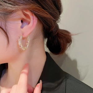 Close-up of golden C-shaped hoop earrings with rectangular baguette cubic zirconia