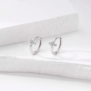Macro detail of S925 sterling silver hoop earrings with diamond cross charm engraving