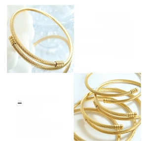 Detail of 18K gold plated titanium steel cable bracelet with metal bead ends