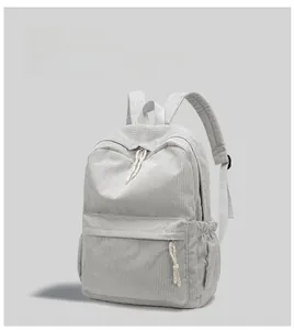 Detail of gray corduroy backpack showing soft fabric texture and zipper with rope puller