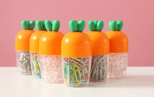 Detailed view of carrot-shaped office stationery kit with paperclips and pushpins