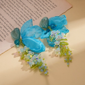 Detail of blue chiffon flower earrings with green resin heart and beaded tassels
