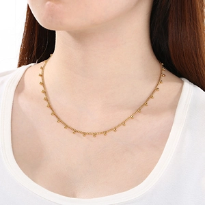 Collier en acier titane doré avec billes de style cubain porté par un mannequin