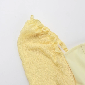 Detailed close-up of light yellow lace texture and puff sleeve design on long dress