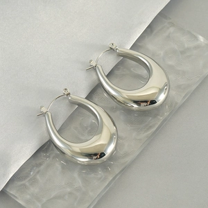 Polished silver stainless steel thick teardrop earrings on a textured glass surface