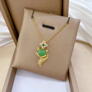 Detailed view of fox pendant with green gemstone and sparkling crystals on gold chain