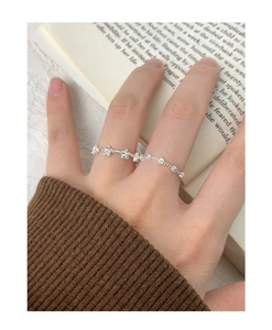 Detailed view of silver flower ring and beaded band worn on hand over vintage books