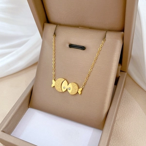 Minimalist gold titanium steel kissing fish necklace with white rhinestones in a beige box
