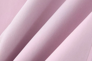 Close-up of soft pink fabric texture with fine weave details on women dress