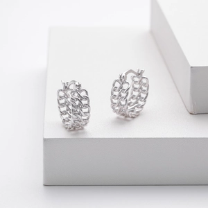 Detailed view of silver geometric chain earrings on a minimalist white background