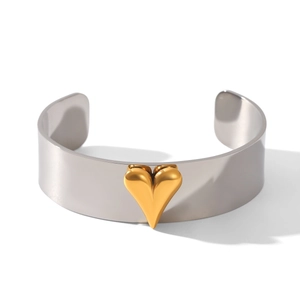 Close-up of a minimalist silver stainless steel open bangle with a 3D golden heart center