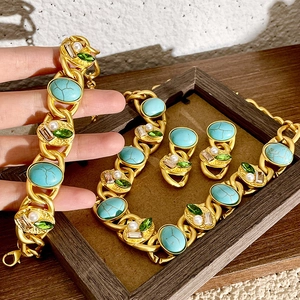 Detail of vintage gold jewelry set with emerald crystals and white pearls on wood frame