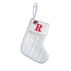 Macro shot of white cable knit Christmas stocking featuring a red embroidered letter R
