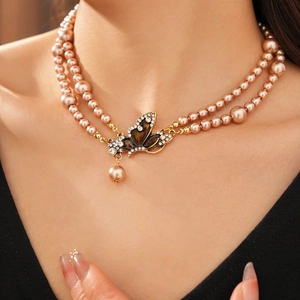 Close-up of double-layer pearl necklace with vintage rhinestone butterfly pendant on a model