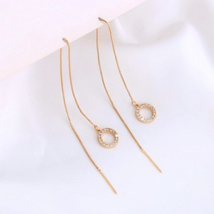 Detail shot of gold star tassel earrings with round cubic zirconia on white silk cloth