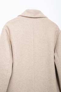 Gros plan de la couture arrière et texture en laine d'un manteau long beige chic