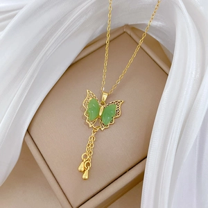 Macro shot of a golden butterfly pendant with green jade wings and tassel chains