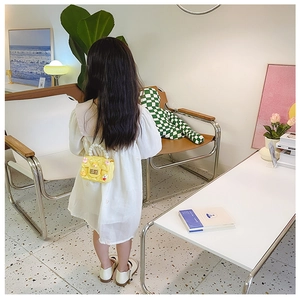Girl's yellow crossbody bag with pearl handle and cartoon duck shown on a model