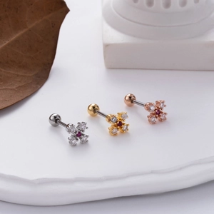 Macro detail of screw-back flower stud earrings with zircon inlay on white stone surface