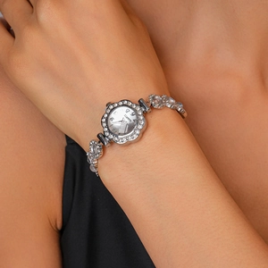 Detail of silver quartz watch featuring flower bezel with rhinestones and purple gemstones