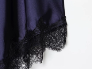 Détail de la robe en satin violet foncé avec bordure en dentelle noire et texture soyeuse