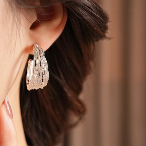 Macro shot of a twisted multi-strand silver hoop earring on a model ear lobe