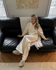 Detail of a beige half-zip sweatshirt and wide-leg trousers set on a leather sofa