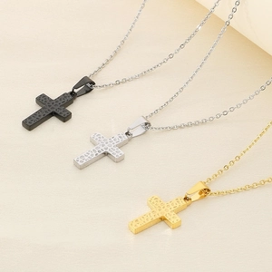 Detailed view of three hammered cross pendants in black, silver, and 18k gold finishes