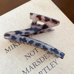 Detailed close-up of tortoise shell leopard print Z-shaped hair claw on textured fabric
