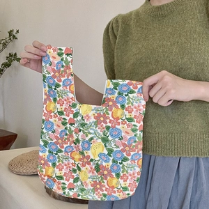 Detail of floral and lemon print cotton canvas wristlet bag held by a model