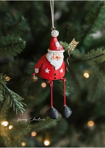 Close-up of hand-painted Santa Claus metal ornament hanging on a Christmas tree