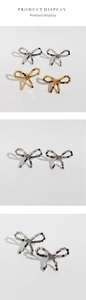 Macro shot of silver and gold bow earrings with square-cut cubic zirconia crystals