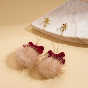 Close-up of snowflake earrings with red velvet bow and beige faux fur pom-pom detail