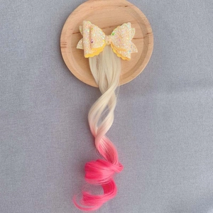 Detail of glitter bow hair clip with gold to pink gradient wavy hair extensions