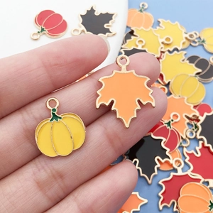 Close-up of alloy enamel maple leaf and pumpkin charms for DIY autumn jewelry making