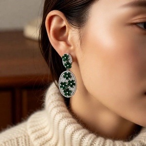 Detail view of vintage flower drop earrings with green zircon inlays on a female model