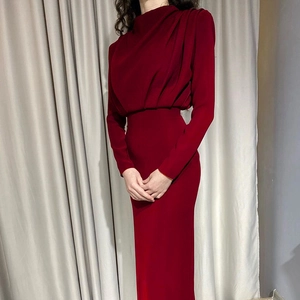 Detail view of the slim-fit waist and flowing fabric of this dark red long sleeve dress