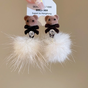 Detail of silver pin earrings with brown flocked teddy bear and white pompom charms