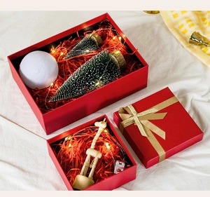 Close-up of red holiday gift boxes with LED lights, mini trees and golden ribbon