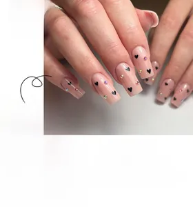 Detail of nude square press-on nails with black heart patterns and colorful rhinestones