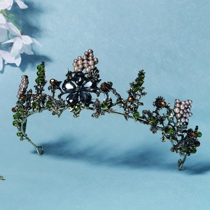 Macro view of vintage bridal crown with green crystals and pearls on bronze metal base