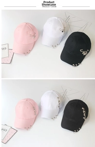 Detailed view of baseball caps with metallic rings, heart pins, and chain decorations