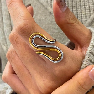 Modern S-shaped two-tone gold and silver stainless steel ring on model hand